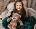 Child holding teddy bear in cozy setting.