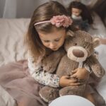 Child holding teddy bear, cozy moment.