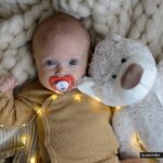 Baby cuddling teddy bear with lights.