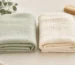 Pale sage bamboo and cream cotton muslin baby blankets shown side by side