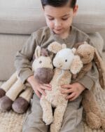 Child holding Cow Cruise and other plush toys