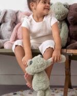 Child holding a green Frog Flex plush toy