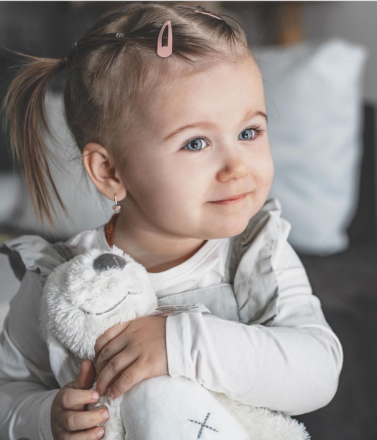 Toddler with a side ponytail hugging a white plush rabbit.