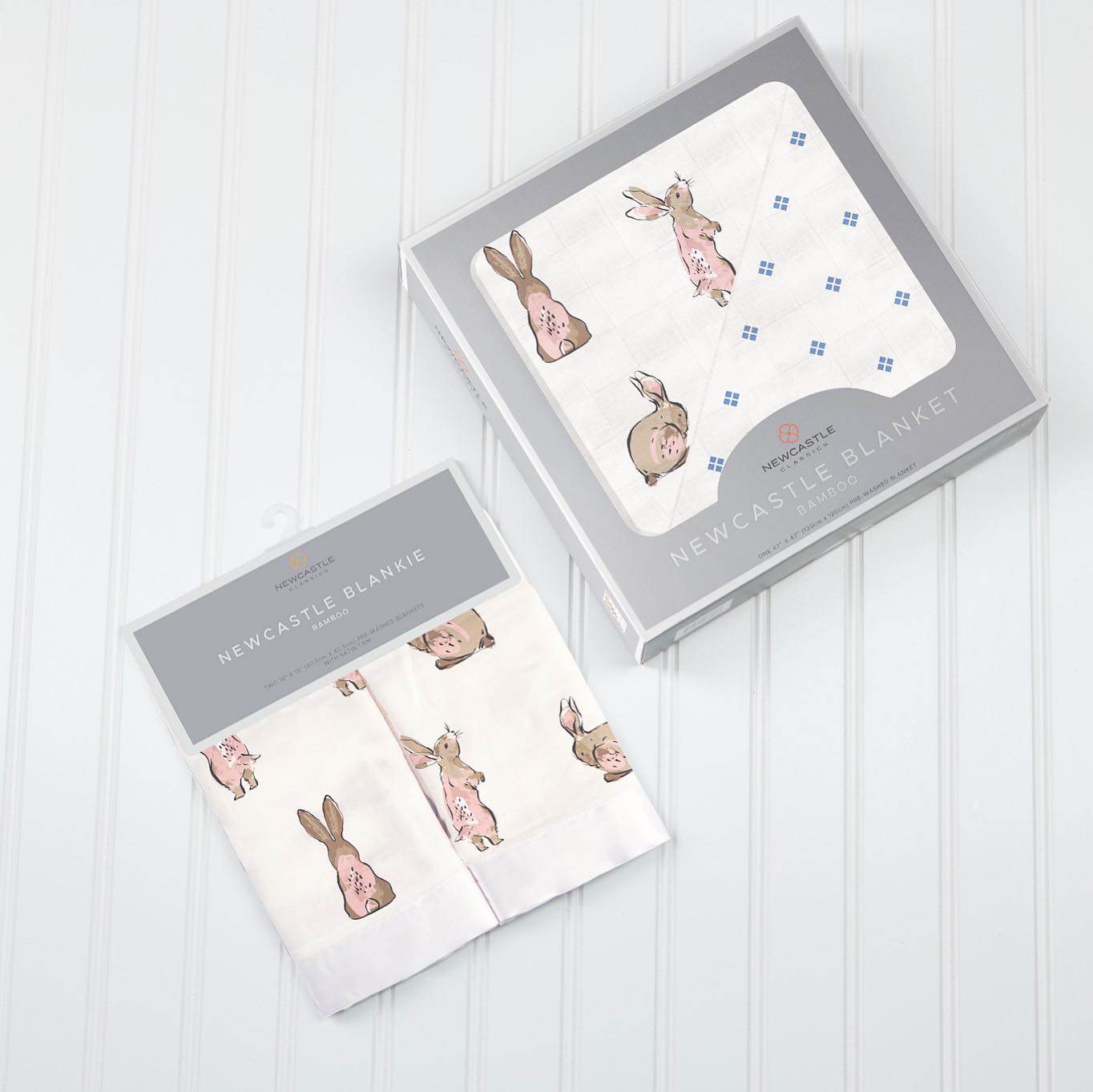 Boxed baby blanket and folded matching cloth with pink bunny print on a white surface.